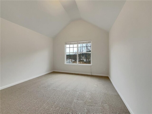 spare room featuring carpet flooring and vaulted ceiling