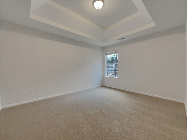 unfurnished room featuring carpet and a tray ceiling