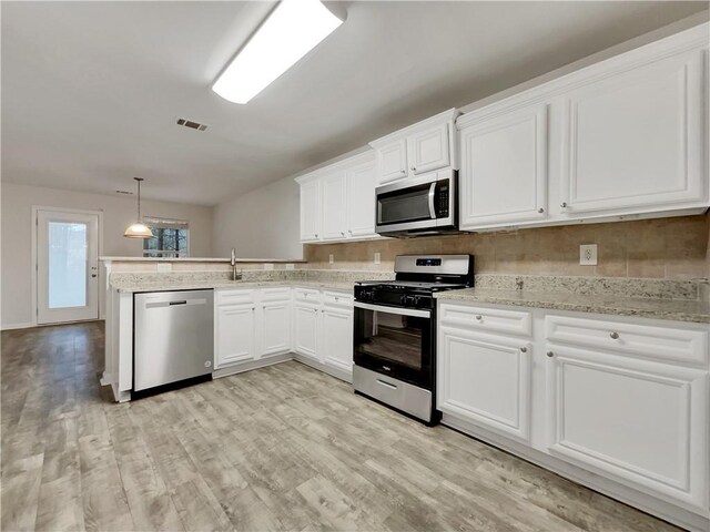 kitchen with white cabinets, decorative light fixtures, light hardwood / wood-style floors, and appliances with stainless steel finishes