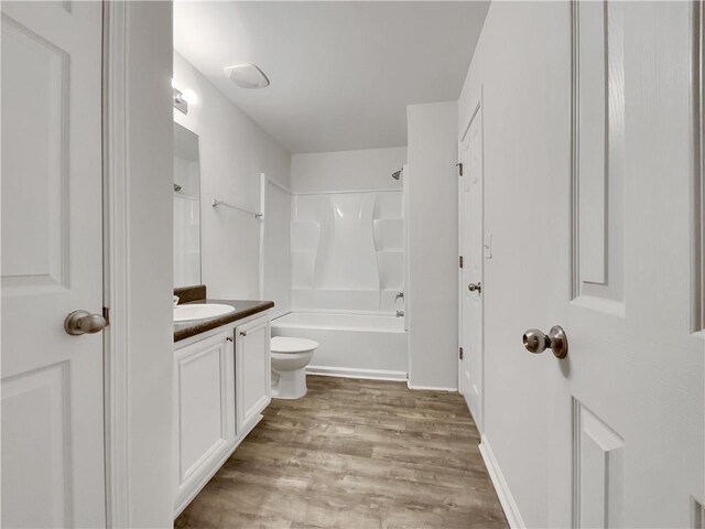 full bathroom with shower / bathing tub combination, vanity, hardwood / wood-style flooring, and toilet