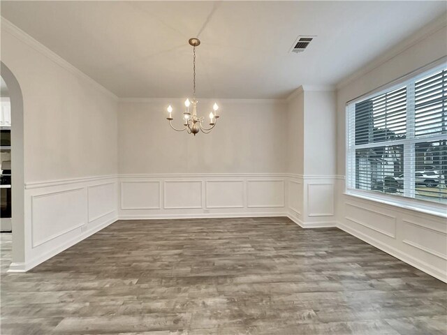 unfurnished dining area featuring hardwood / wood-style flooring, ornamental molding, and an inviting chandelier