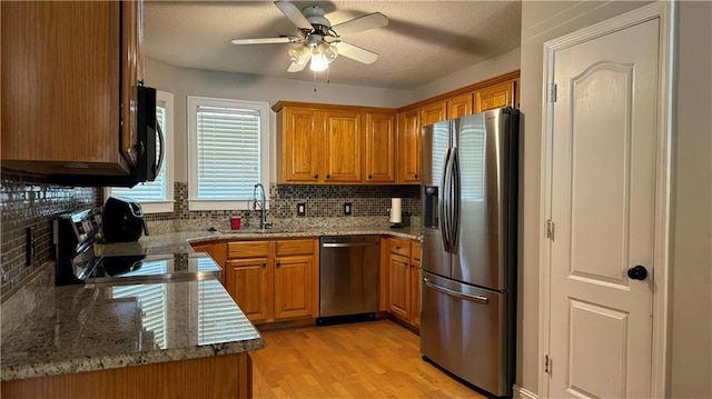 kitchen featuring light hardwood / wood-style floors, ceiling fan, stainless steel appliances, decorative backsplash, and stone counters