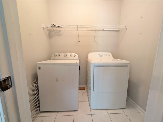 clothes washing area with light tile patterned floors and washer and clothes dryer