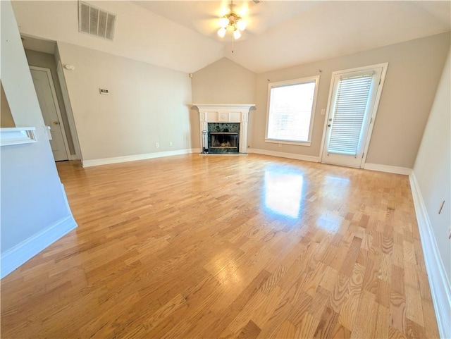 unfurnished living room featuring ceiling fan, light hardwood / wood-style floors, a high end fireplace, and vaulted ceiling