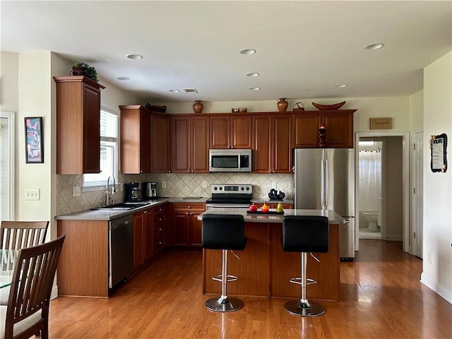 1055 Havenstone Walk, Lawrenceville, GA 30045 - kitchen featuring appliances with stainless steel finishes, light wood finished floors, a kitchen island, a kitchen bar, and decorative backsplash