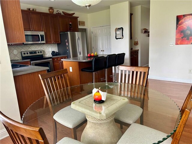 1055 Havenstone Walk, Lawrenceville, GA 30045 - kitchen featuring stainless steel appliances, a center island, decorative backsplash, light wood-style flooring, and a kitchen bar
