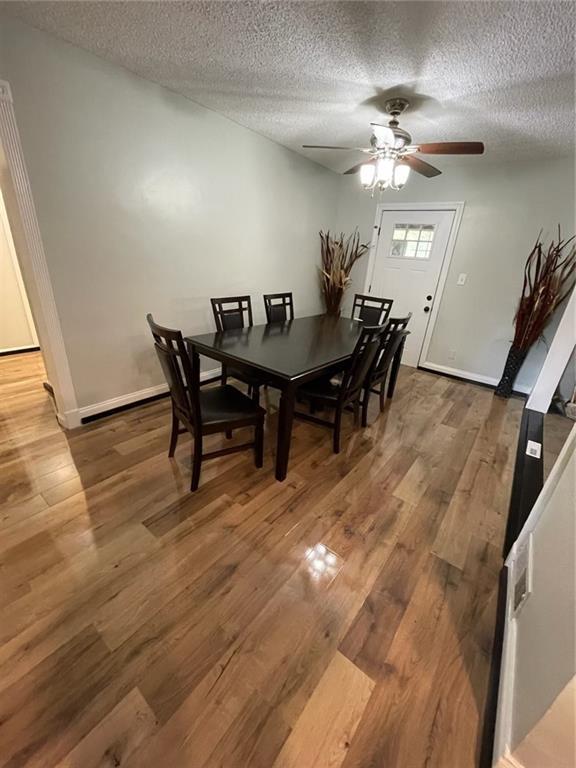 dining area with hardwood / wood-style flooring, ceiling fan, and a textured ceiling