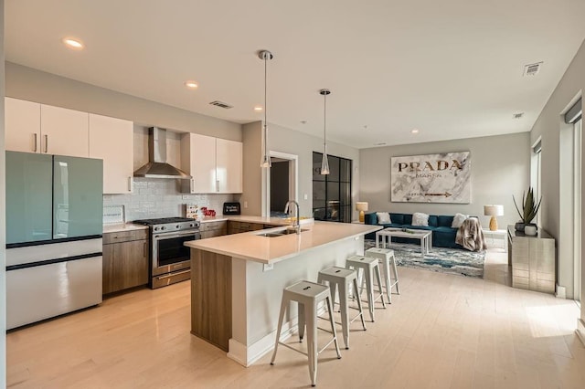 775 Juniper St NE Unit 612, Atlanta, GA 30308 - kitchen featuring wall chimney exhaust hood, stainless steel appliances, a sink, light wood-style flooring, and a kitchen breakfast bar