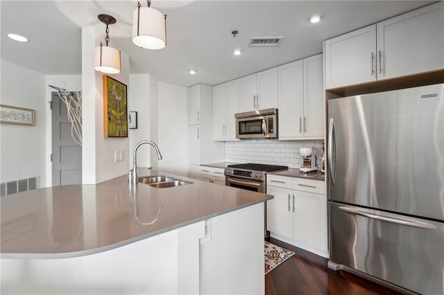 kitchen featuring white cabinetry, stainless steel appliances, sink, and hanging light fixtures