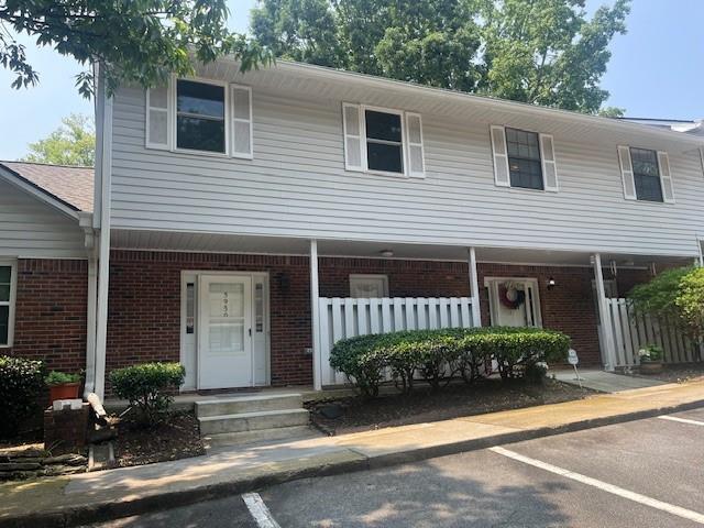 5950 Wintergreen Rd, Norcross, GA 30093 - townhome / multi-family property featuring brick siding, covered porch, and uncovered parking