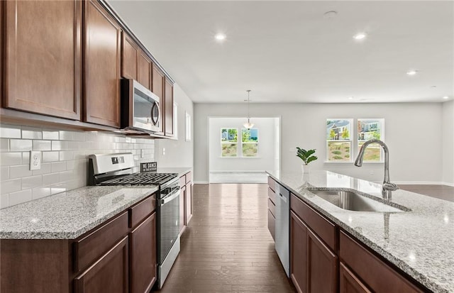 kitchen featuring light stone countertops, appliances with stainless steel finishes, sink, and pendant lighting