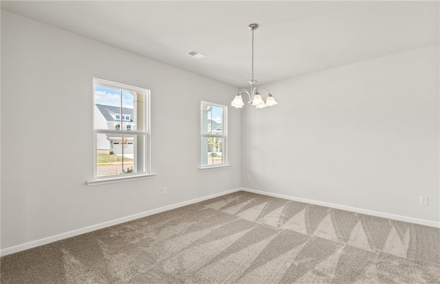 carpeted empty room with an inviting chandelier