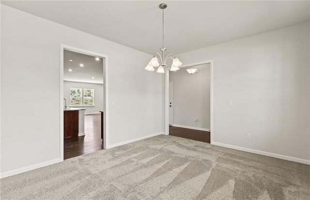 carpeted spare room with a notable chandelier