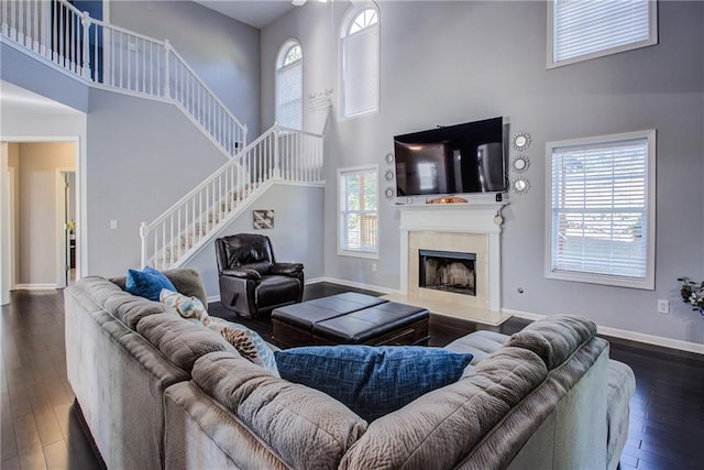 living room featuring a towering ceiling, a fireplace, and dark hardwood / wood-style flooring