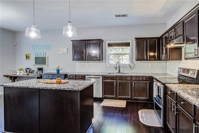 kitchen with a kitchen island, appliances with stainless steel finishes, decorative light fixtures, sink, and dark wood-type flooring