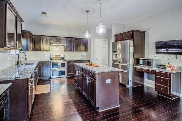 kitchen with sink, dark brown cabinets, hanging light fixtures, appliances with stainless steel finishes, and a kitchen island