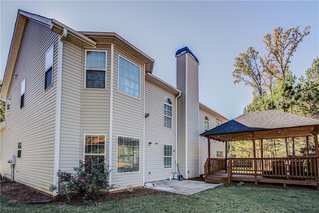 back of property featuring a gazebo, a yard, a wooden deck, and a patio