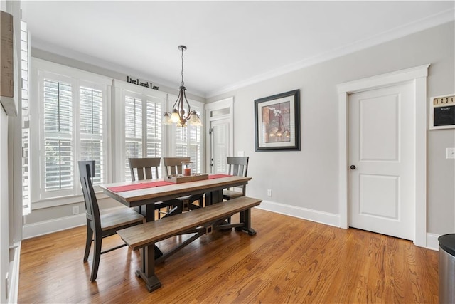 dining space featuring light hardwood / wood-style floors, ornamental molding, and a notable chandelier