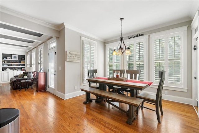 dining area featuring built in shelves, light wood-type flooring, ornamental molding, and a notable chandelier