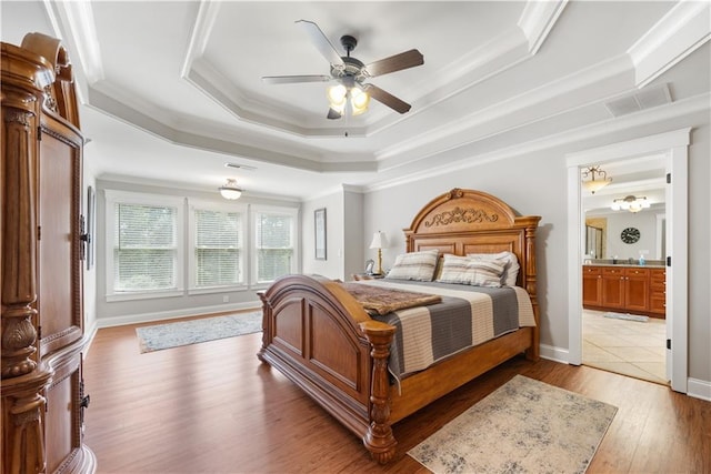 bedroom with ceiling fan, light hardwood / wood-style flooring, crown molding, and a tray ceiling