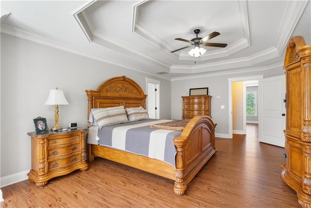 bedroom with a tray ceiling, ceiling fan, crown molding, and wood-type flooring