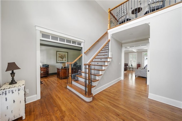 stairway featuring hardwood / wood-style floors, a towering ceiling, and ornamental molding