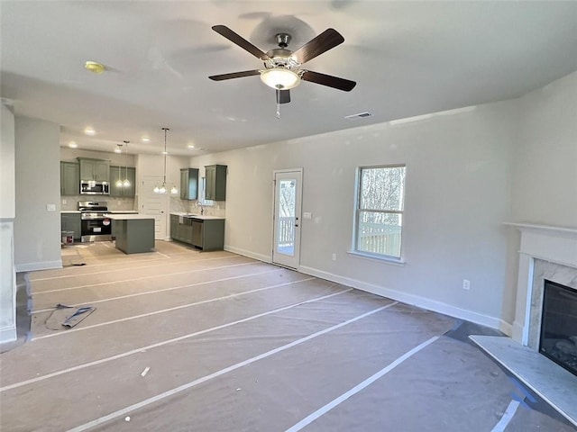 unfurnished living room with ceiling fan, a fireplace, and sink