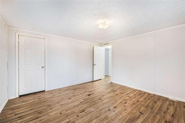 spare room featuring a textured ceiling, wood finished floors, and visible vents