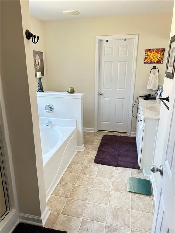 bathroom featuring a bath, tile patterned floors, and vanity