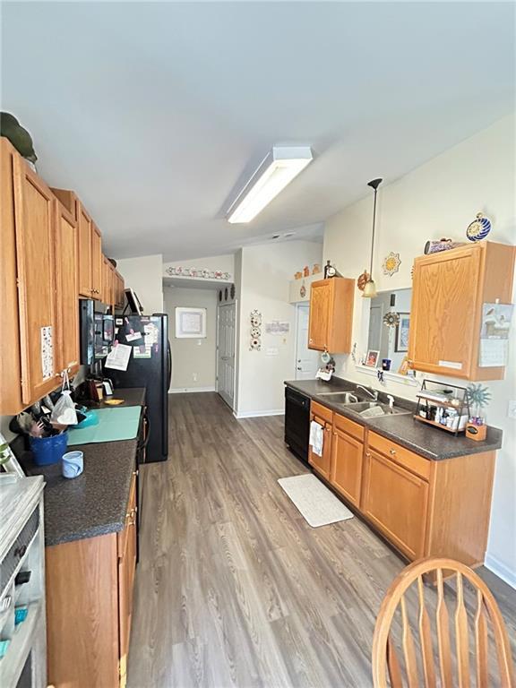 kitchen with light wood-type flooring, sink, pendant lighting, and black appliances