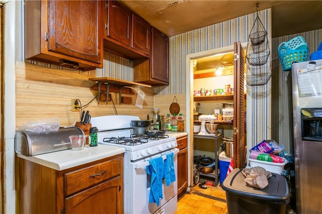 379 Utoy Cir SW, Atlanta, GA 30331 - kitchen with white gas range, wallpapered walls, light countertops, and stainless steel refrigerator with ice dispenser