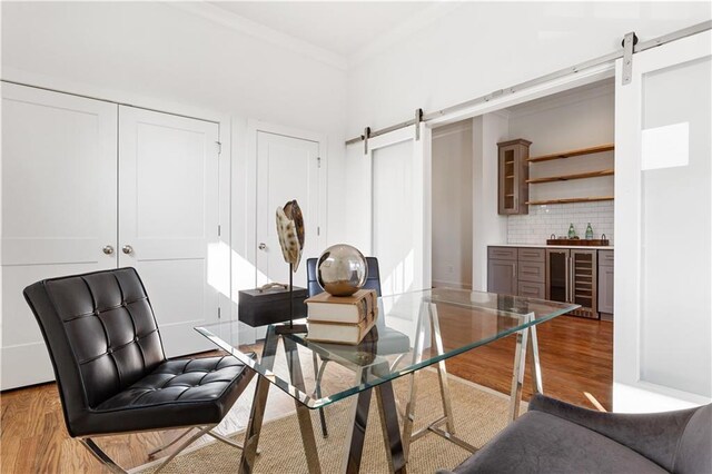 interior space with hardwood / wood-style flooring, ornamental molding, beverage cooler, and a barn door