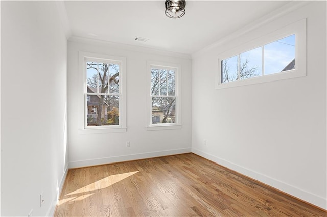 spare room featuring ornamental molding and light hardwood / wood-style floors