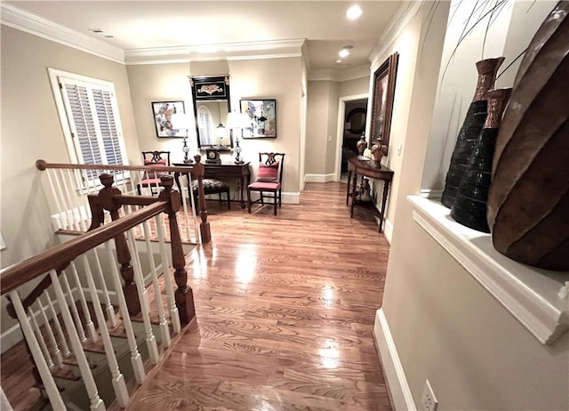 corridor featuring baseboards, ornamental molding, wood finished floors, and an upstairs landing