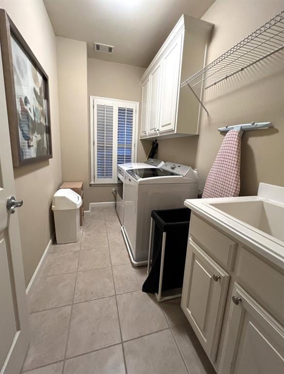 clothes washing area with visible vents, baseboards, light tile patterned flooring, cabinet space, and separate washer and dryer