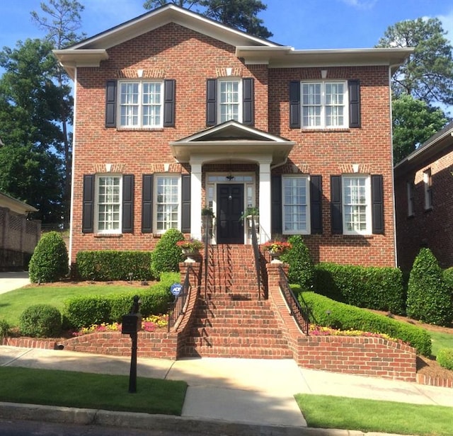 view of front facade featuring brick siding and stairway