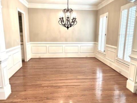 unfurnished dining area with crown molding, a chandelier, and dark wood-type flooring