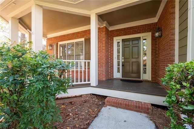 property entrance featuring covered porch and brick siding