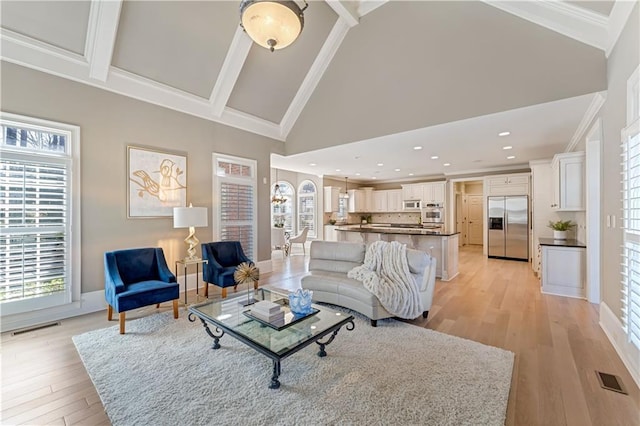 living area featuring light wood finished floors, visible vents, high vaulted ceiling, and crown molding