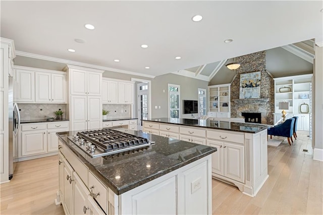 kitchen with open floor plan, appliances with stainless steel finishes, a center island, and light wood-type flooring