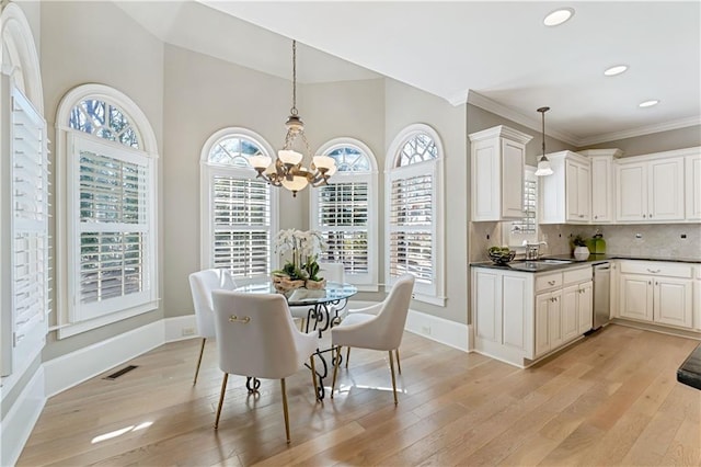 dining room featuring visible vents, crown molding, baseboards, light wood-style floors, and a notable chandelier