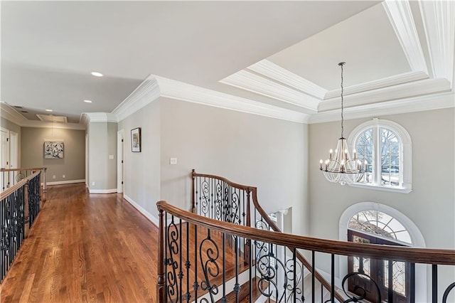 corridor with wood finished floors, a notable chandelier, an upstairs landing, and a healthy amount of sunlight