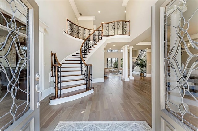 entrance foyer featuring decorative columns, baseboards, wood finished floors, and ornamental molding