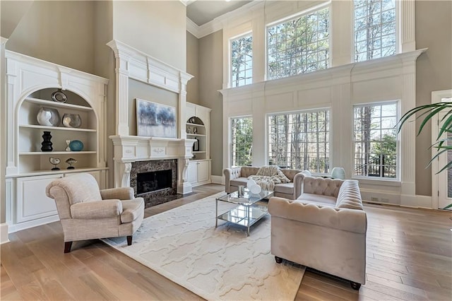 living area with a high ceiling, wood finished floors, and a high end fireplace