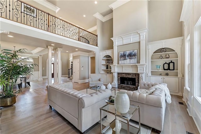 living room featuring built in features, ornate columns, and ornamental molding