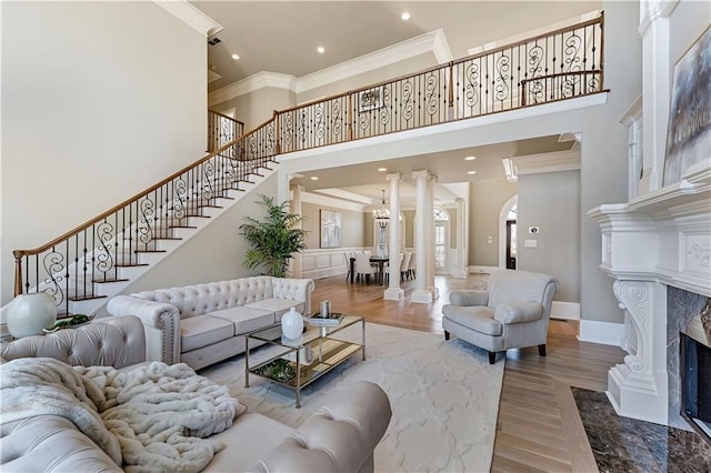 living area with stairs, a premium fireplace, ornamental molding, a towering ceiling, and wood finished floors