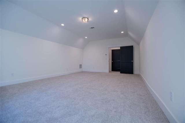 bonus room with vaulted ceiling and light colored carpet