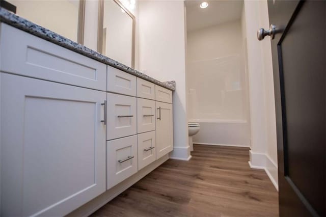 full bathroom featuring vanity, bathtub / shower combination, hardwood / wood-style floors, and toilet