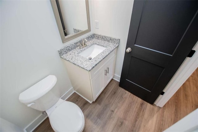 bathroom with hardwood / wood-style flooring, vanity, and toilet