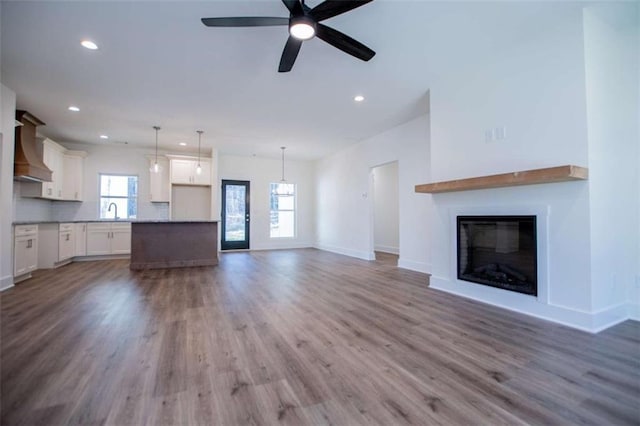 unfurnished living room featuring ceiling fan, wood-type flooring, and sink